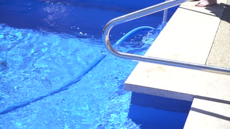 close up man vacuuming blue pool sunny day