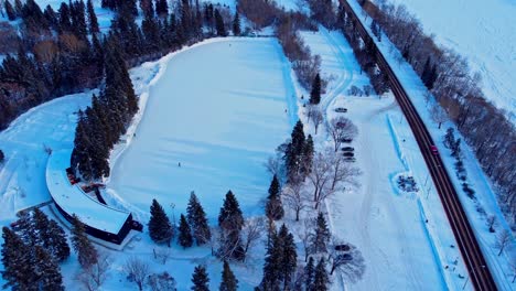 2-8edm victoria park aerial drone hold over manmade pandemic restriction sunset winter snow covered capital city edmonton largest outdoor skating arena in alberta with only 4 people out sliding around