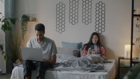 couple in bedroom using devices
