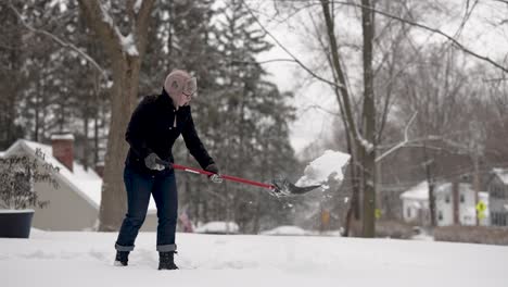 woman shovels snow in a suburban neighborhood, slow motion