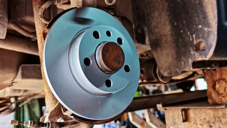 Newly installed rear brake disc on vehicle during repair work showing clean rotor surface