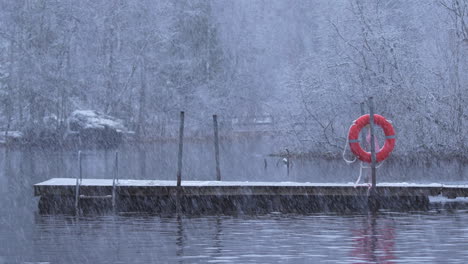 Starker-Schneefall-An-Einem-Fluss-Mit-Dock-Und-Rettungsring,-Stativaufnahme