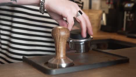 barista using distribution tool with portafilter to avoid air pocket in coffee