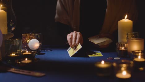 primer plano de una mujer dando una lectura de cartas de tarot en la mesa a la luz de las velas 8