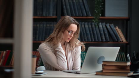mujer cansada profesora de ciencias maestra trabajando portátil en la biblioteca sintiendo dolor de cuello por exceso de trabajo