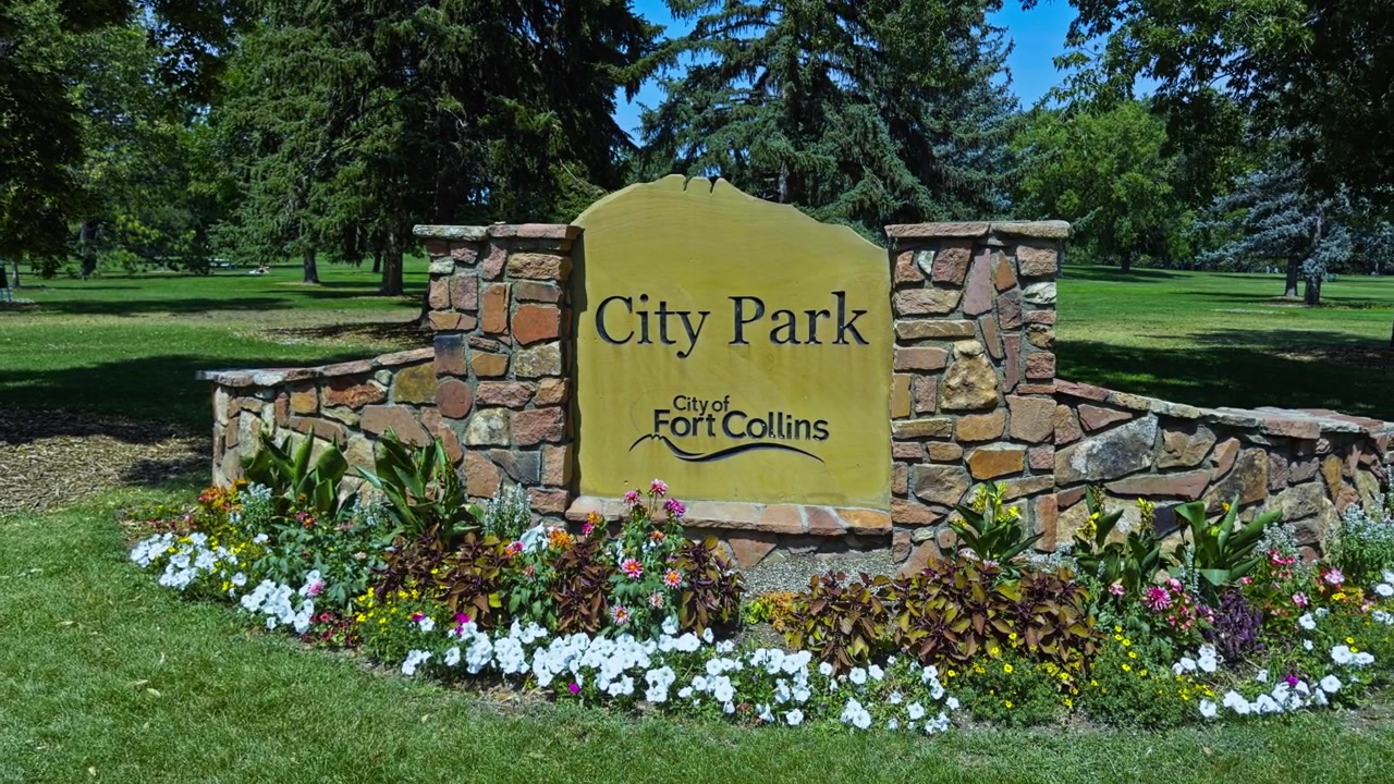 Il cartello d'ingresso del City Park è incorniciato da aiuole fiorite colorate a Fort Collins, Colorado