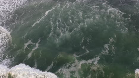 discover the beauty of the rugged cliffs in the background, as the drone shot slowly pans down to reveal the mesmerizing crashing waves below