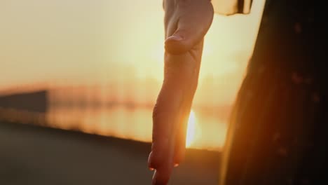 hand reaches out to the golden sunset