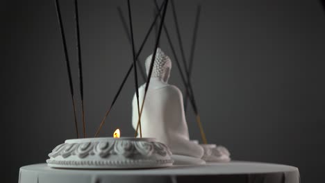 sacred buddhist idol displayed on a rotating platform with lit candles and incense sticks