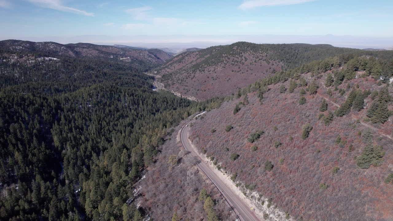 아래의 숲과 함께 산의 고속도로를 따라 운전하는 자동차, 드론 항공기