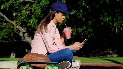 mujer usando teléfono móvil mientras tiene jugo 4k