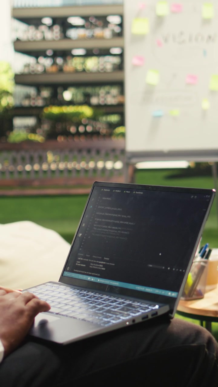 Vertical Video African american businessman coding on laptop terminal window on terrace