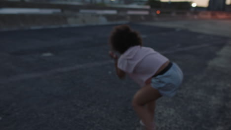 Mujer-Bailando-Bailarina-Callejera-De-Raza-Mixta-Con-Funky-Afro-Realizando-Movimientos-De-Hip-Hop-Estilo-Libre-Disfrutando-De-La-Expresión-De-Danza-Moderna-En-La-Ciudad-Al-Atardecer