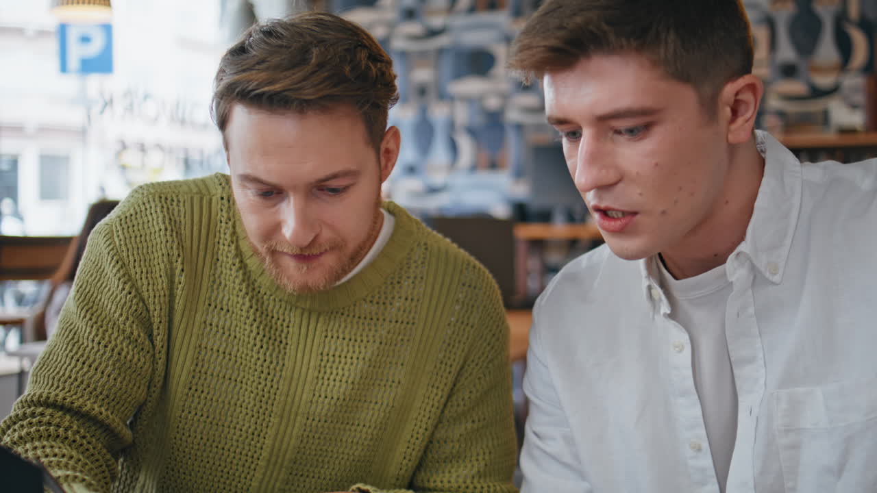 Closeup focused designers brainstorming office. Two guys coworkers looking notes