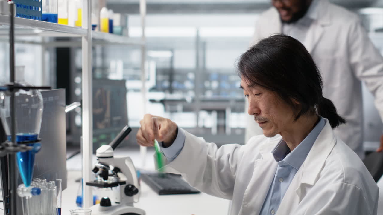 Vertical video Senior biochemist shaking laboratory glassware filled with green solution