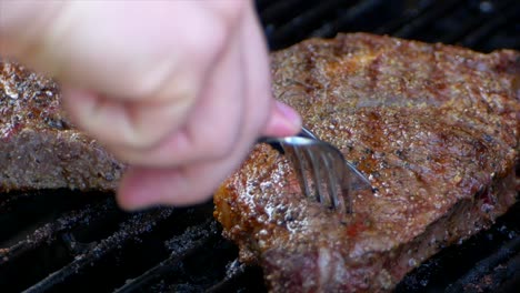 a fork and knife cutting a rib eye steak on the grill to see how pink the meat is on the inside whether it’s rare, medium or well done in slow motion