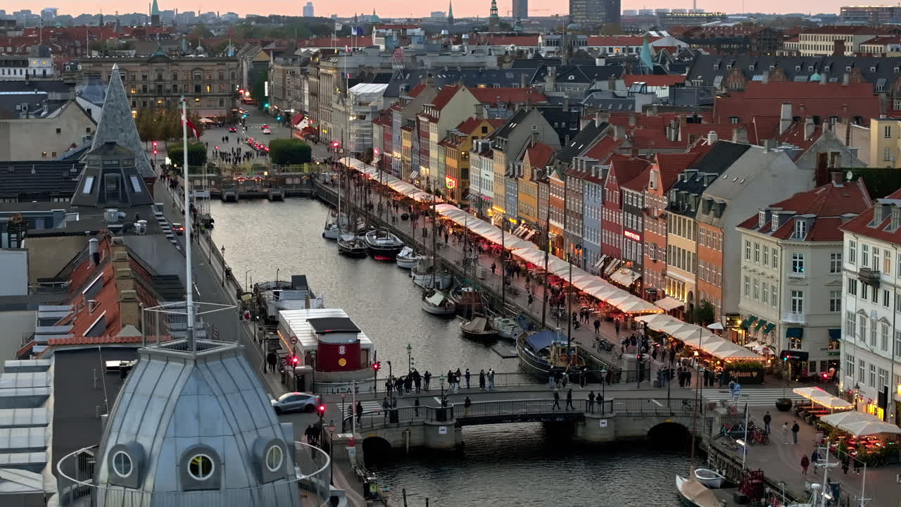 Luftfoto med drone af Nyhavns havnefront, kanal og forlystelseskvarter i København, Danmark om aftenen