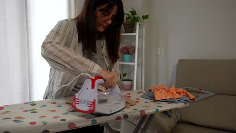 woman ironing baby clothes at home, calm indoor scene with soft natural lighting