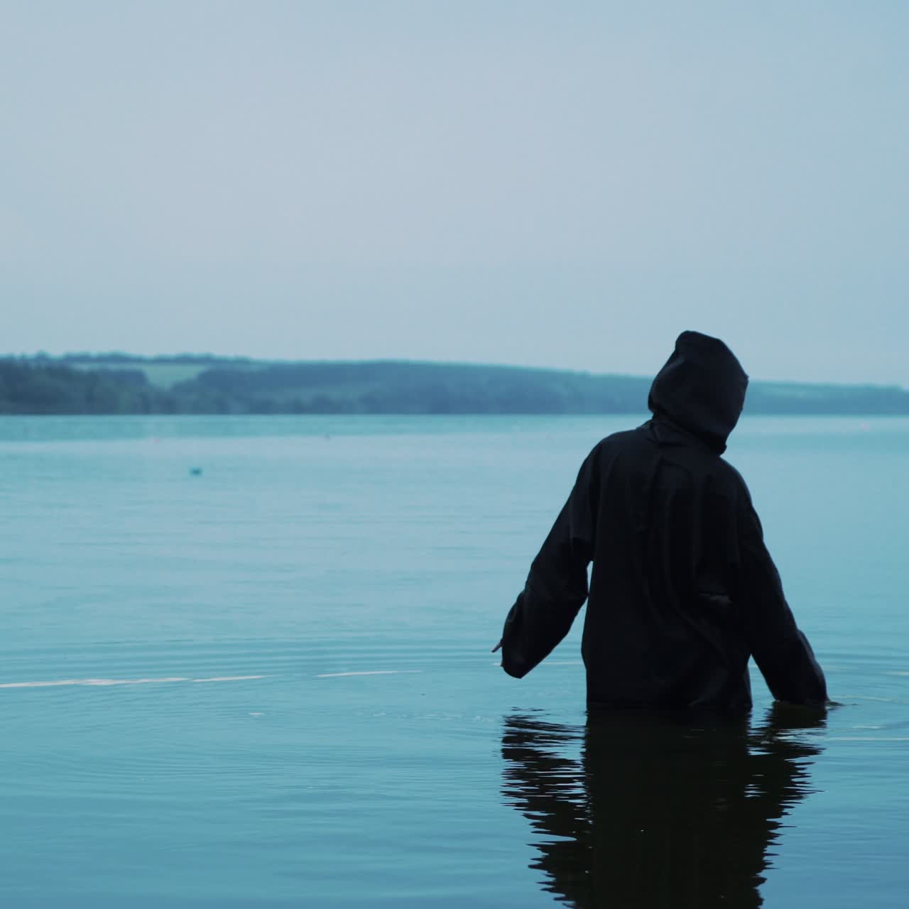 Scary figure in black mantle in the river. Halloween costume
