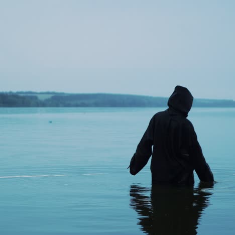 scary figure in black mantle in the river. halloween costume