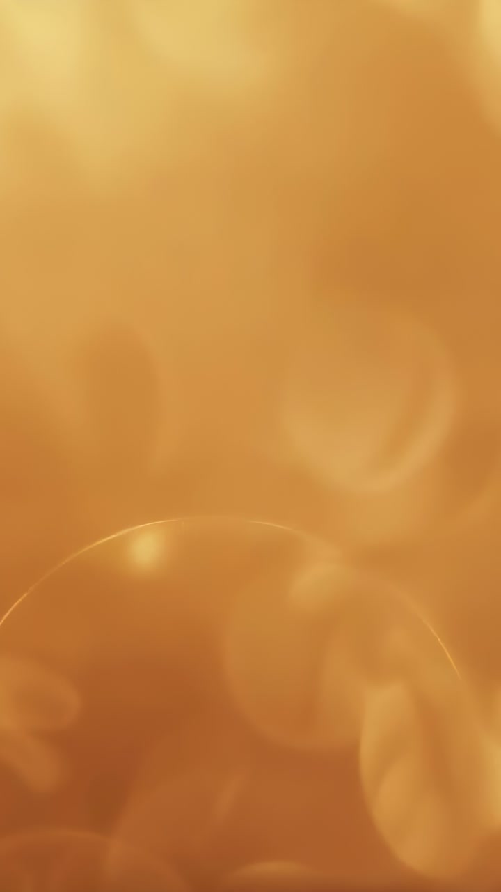 Vertical video: Shifting warm golden bokeh pattern shimmering in close-up, focus slowly changing