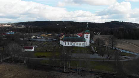 Drone-Volando-Hacia-La-Iglesia-Bjorketorp-Rodeada-De-árboles-Desnudos-En-La-Ciudad-De-Ravlanda,-Harryda,-Suecia