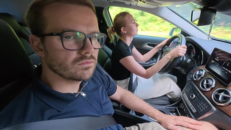 Un istruttore di guida supervisiona un allievo conducente durante una lezione pratica di guida all'interno di un veicolo per la scuola guida. Concetto di educazione alla guida, sicurezza stradale e apprendimento della guida.
