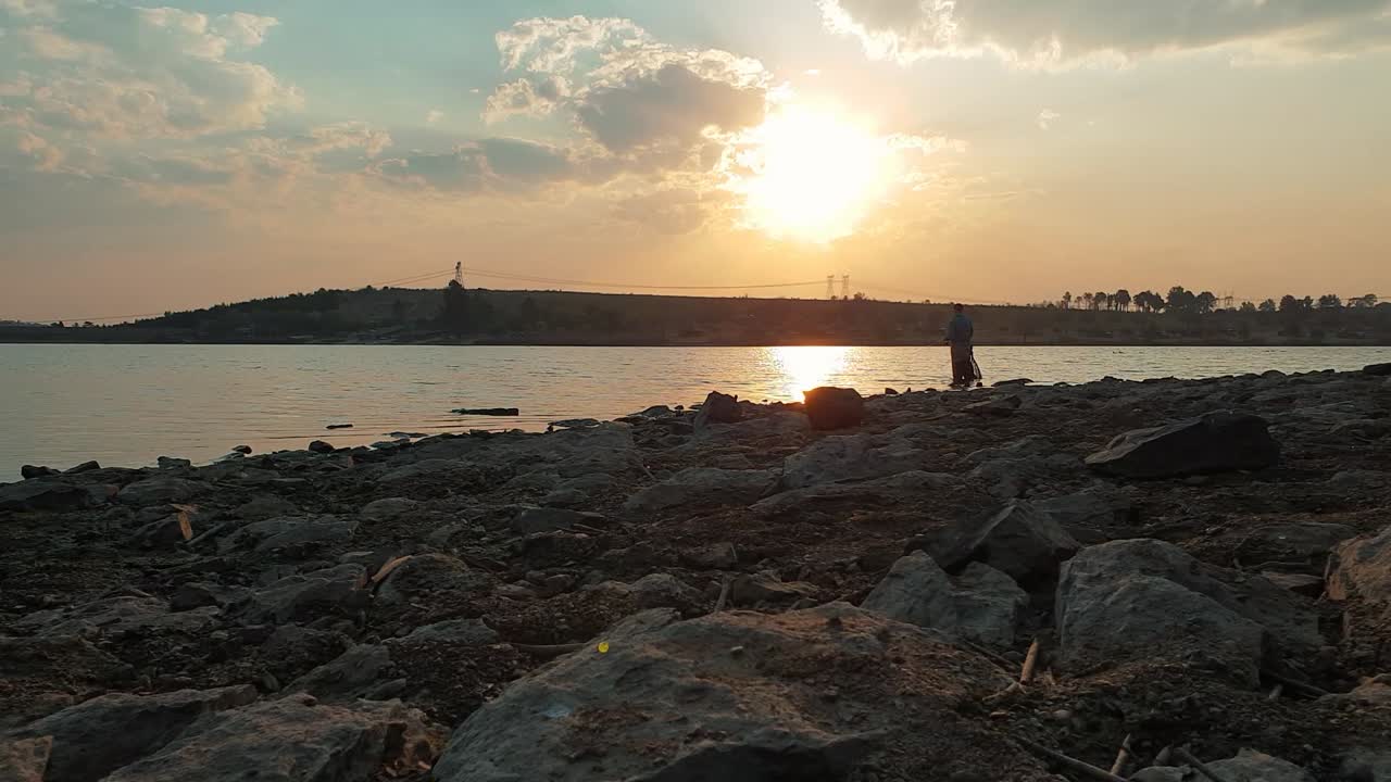 Um homem pescando robalo em um lago durante uma tarde calma e ensolarada