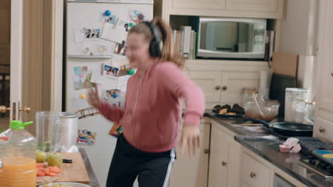 happy teenage girl dancing in kitchen having fun celebrating weekend performing funny dance moves listening to music wearing headphones