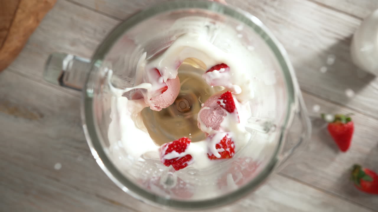 batido de helado de fresa mezclado en una licuadora de vidrio en cámara lenta, vista de arriba, dentro del dispositivo