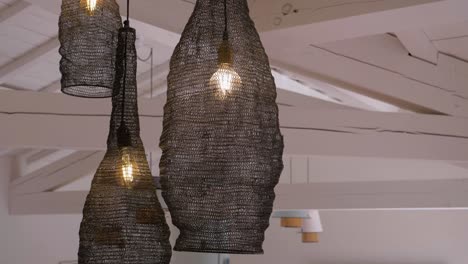 close up moving clip of three contemporary hanging light shades in large room