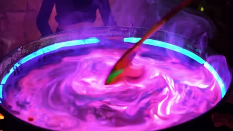 a cauldron of purple potion boils over a fire with smoke