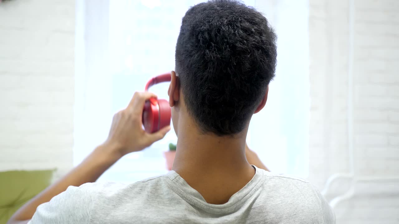 African Man Removing Red Headphones, Back View