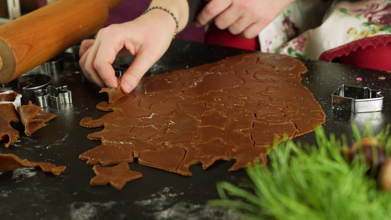 Child carefully takes cookie shapes from gingerbread dough during Christmas prep