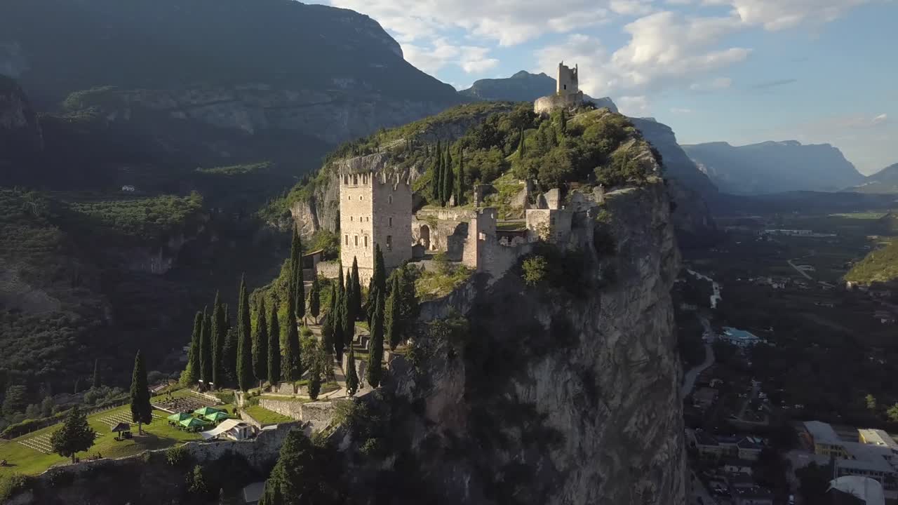 Vista dall'elicottero di alcune antiche rovine sulla cima di una scogliera nelle Dolomiti italiane, Castello di Arco, Riva del Garda