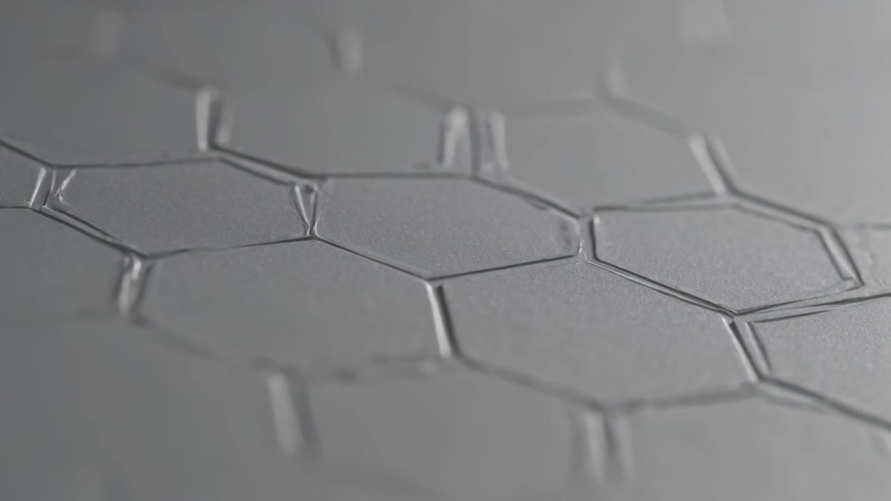 Pulling camera micro pull revealing embossed hex panel in studio light showing raised seams, glints