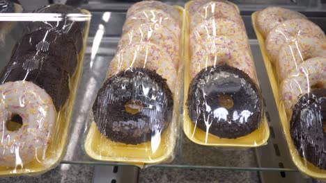 donuts glazados con salpicaduras coloridas en paquetes de plástico en el estante de la tienda