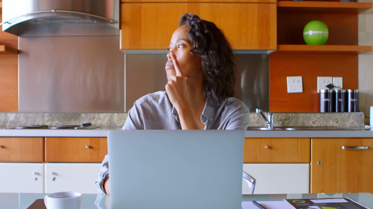 Woman using laptop in kitchen 4k