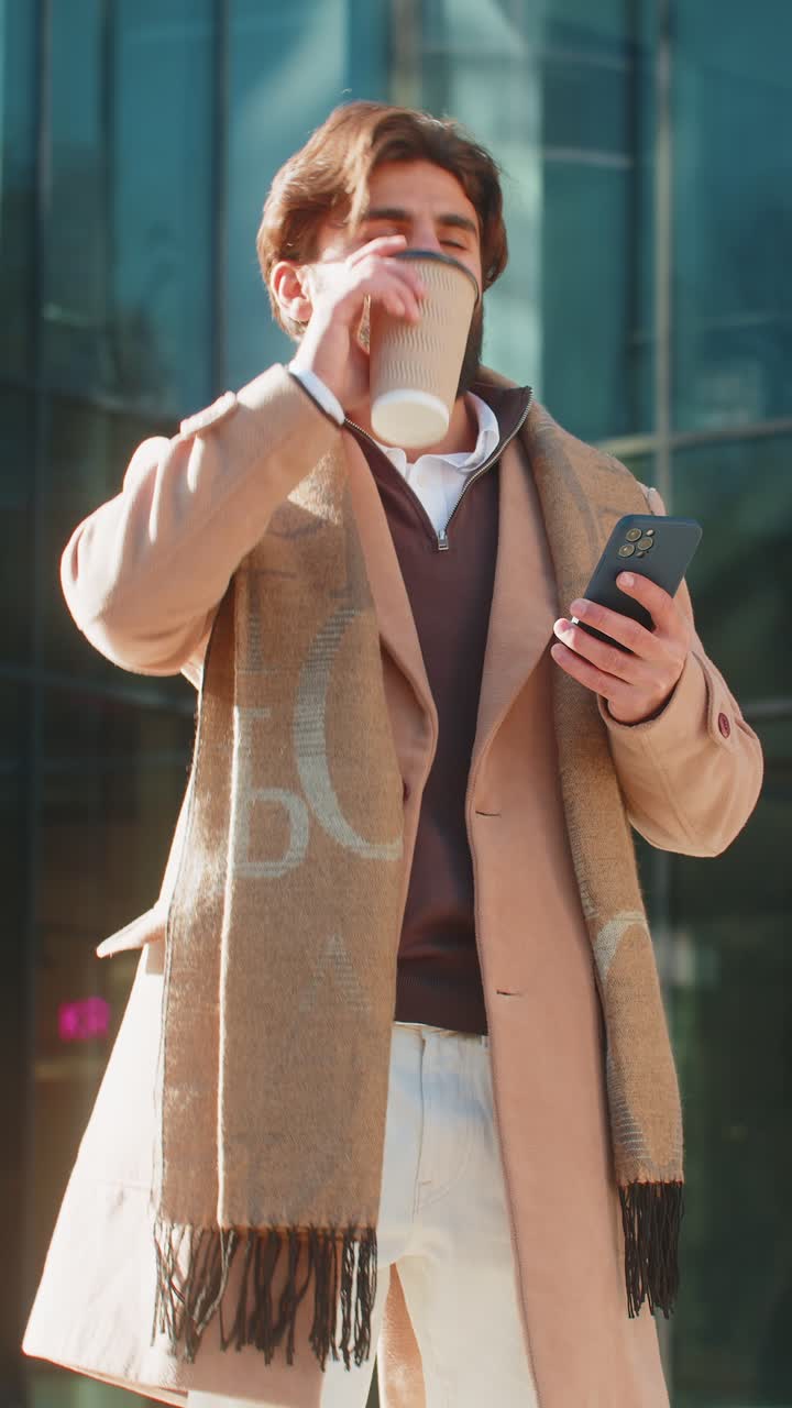 Happy indian business man tourist enjoying morning coffee hot drink sitting on city downtown street