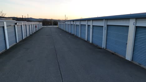 Aerial-flight-between-old-american-Rental-Self-Storage-Unit-Facility-during-golden-sunset-in-background