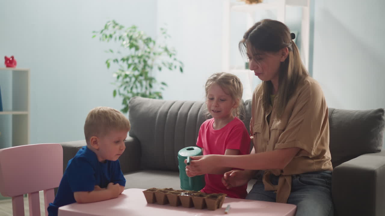 niña riega semillas en una bandeja de plántulas con su madre y su hermano