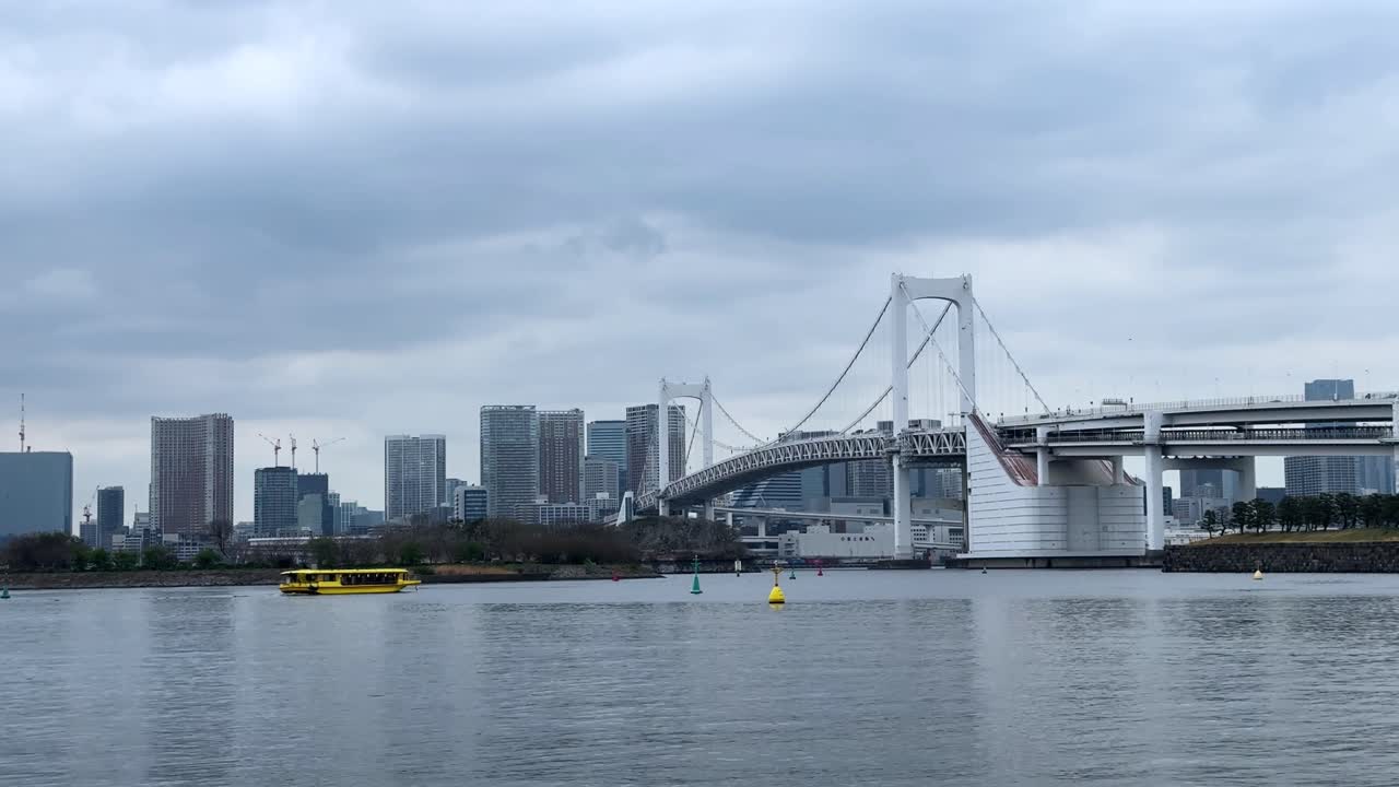 Modern city skyline and Rainbow Bridge in Tokyo on a cloudy day by the water