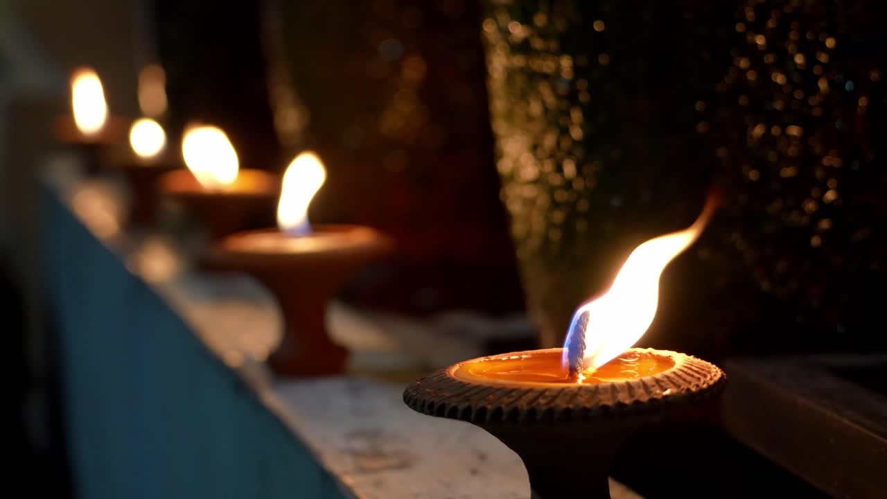 Close-up of Lanna-style clay lamps glowing in a line during nighttime celebrations