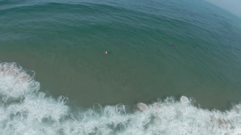 Aerial-circular-view-over-seascape-with-people-swimming-in-the-waves