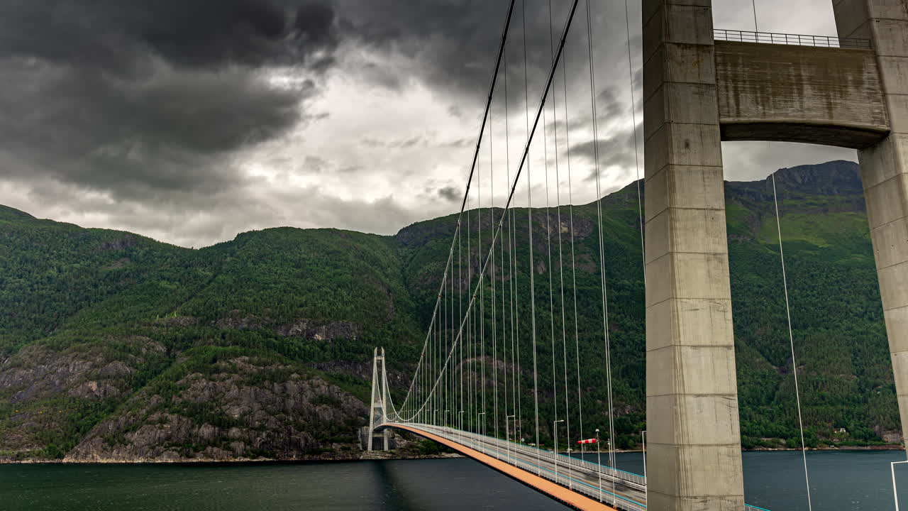 tiempo de flujo de tráfico y nubes de mal humor sobre el puente hardanger, vestland