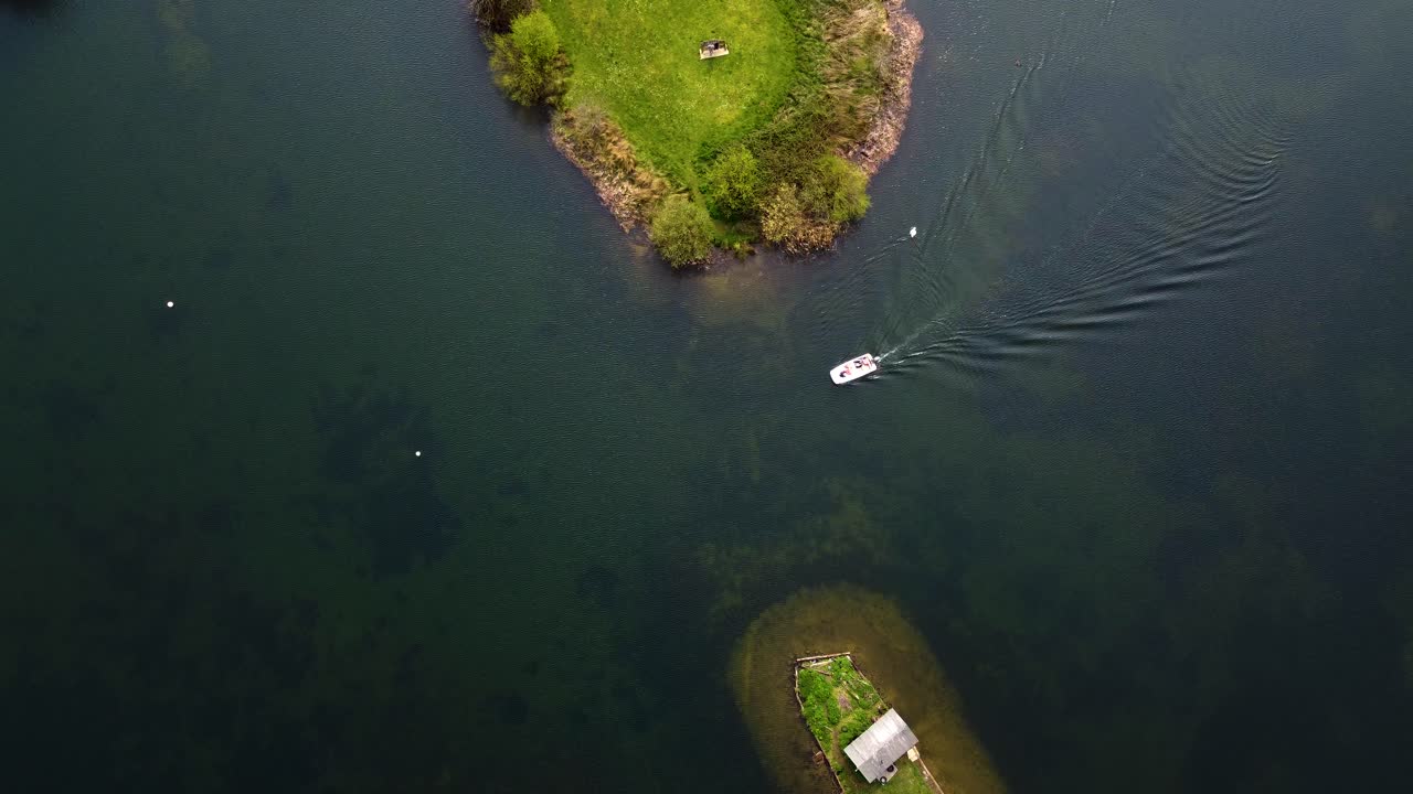 두 섬 사이의 수로를 가로지르는 배의 위상 - 작은 열대 섬과 함께 순수한 파란색의 은 바다 물을 가로질러 가는 빠른 배의 공중 사진