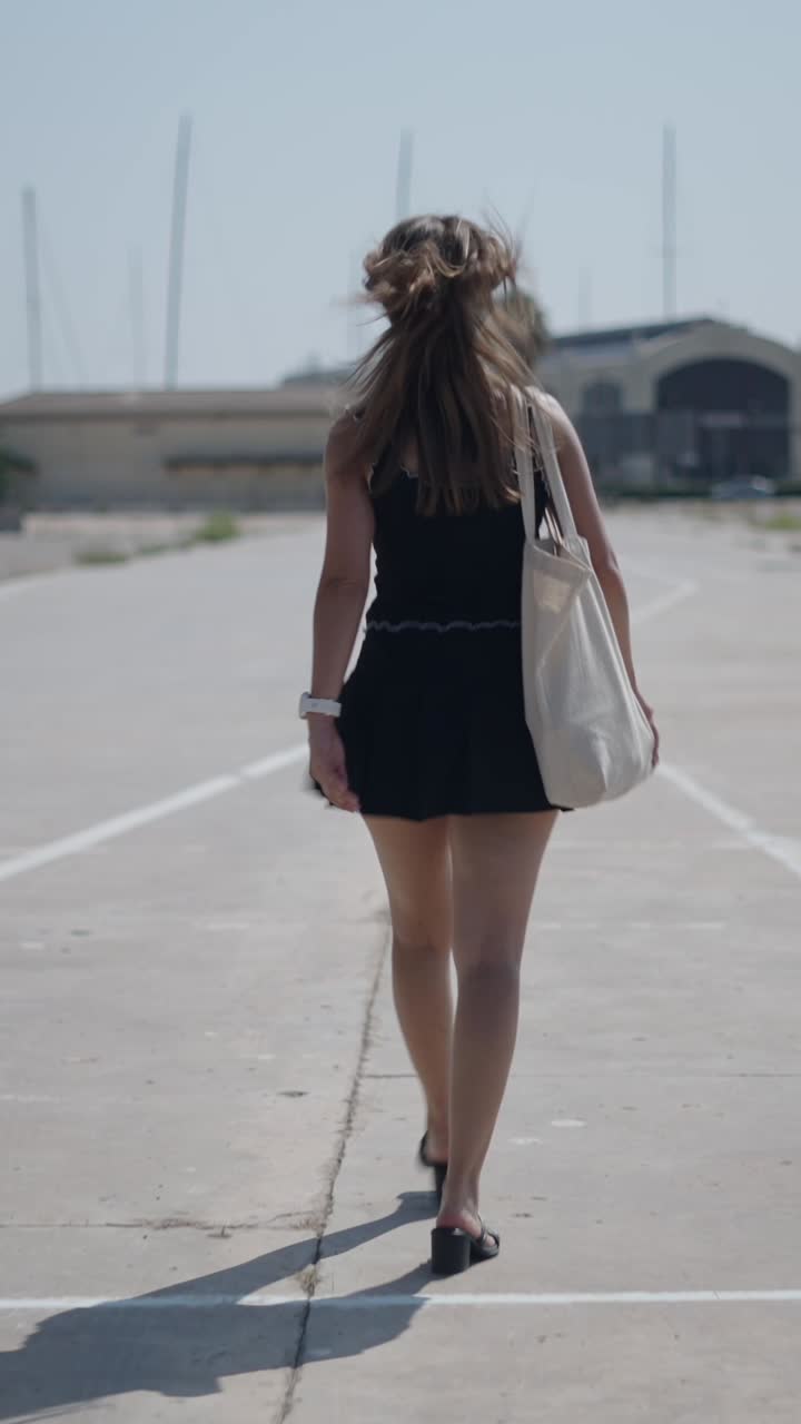 Donna con vestito nero che cammina all'aperto in una giornata di sole