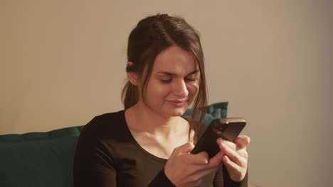 una chica feliz sonriendo enviando mensajes de texto en su teléfono - de cerca