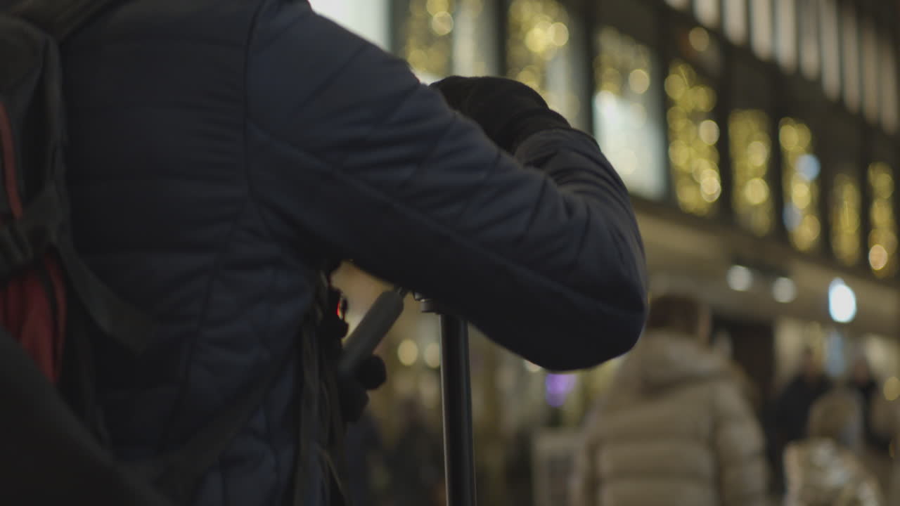 사진작가는 밤에 도심의 거리를 포착하기 위해 삼각대의 카메라를 조정한다