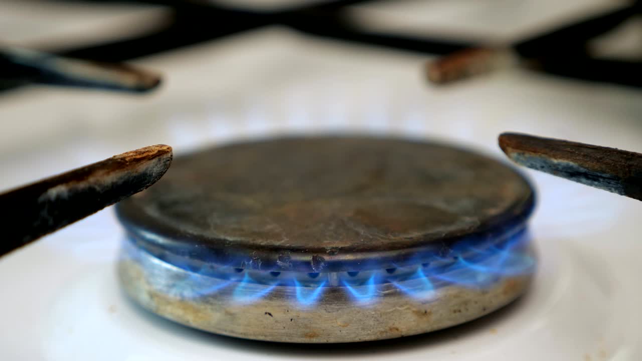 가스 스토브 버너의 클로즈업으로 불을 켜고 있습니다.